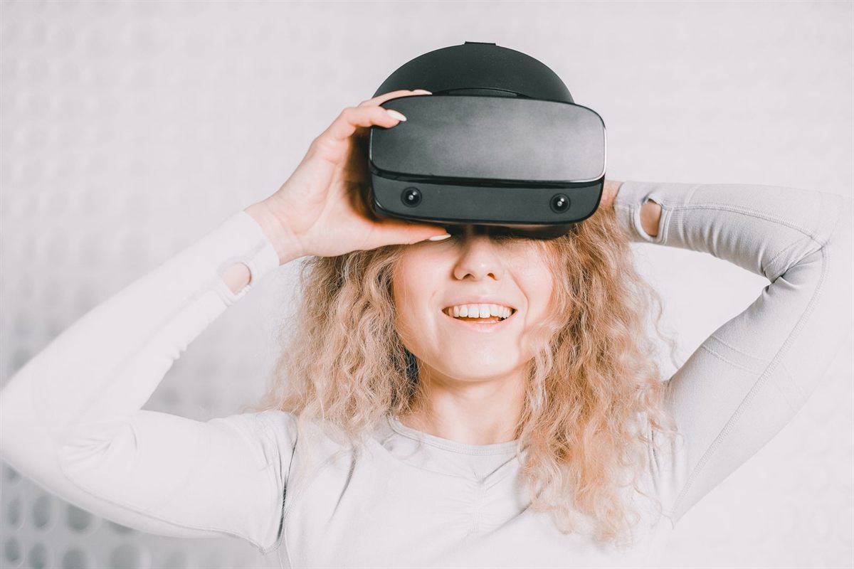 A smiling woman wearing a virtual reality headset at home
